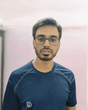 a man with glasses and a beard wears a blue shirt with the letter q on the front