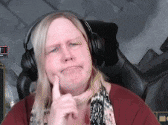 a woman wearing headphones is sitting in a chair and making a funny face .