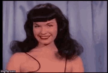 a woman with black hair and red lips is smiling and looking at the camera .