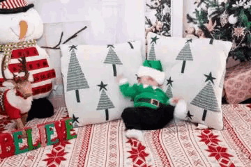 a baby dressed as an elf is laying on a couch with christmas decorations .