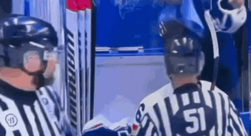 two hockey players are standing next to each other in a locker room .