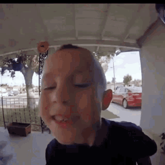 a young boy is standing on a porch with his eyes closed and his mouth open