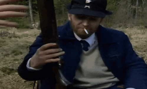 a man smoking a cigarette while holding a gun with the letter x on it