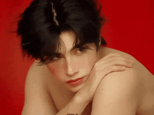 a man without a shirt has his hand on his shoulder in front of a red background that says updoom on it