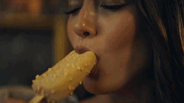 a woman with her eyes closed is eating an ice cream bar