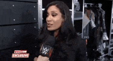 a woman is talking into a microphone while standing in front of a locker room .