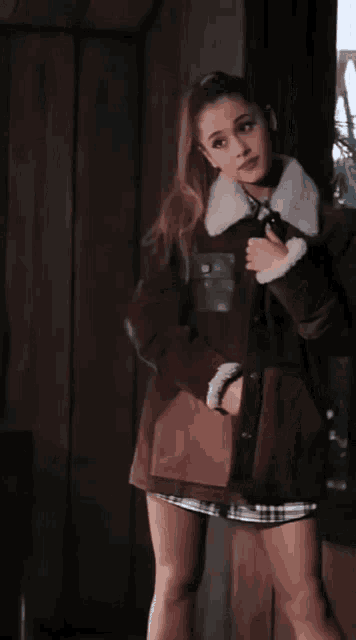 a woman wearing a brown coat with a white collar