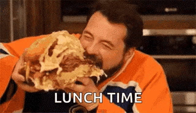 a man with a beard is eating a very large hamburger .