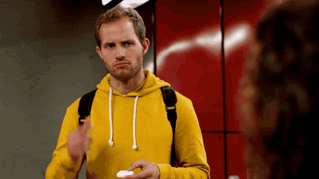 a man wearing a yellow hoodie is holding a white object