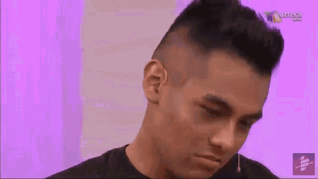 a close up of a man 's face with a purple background and azteca uno in the corner