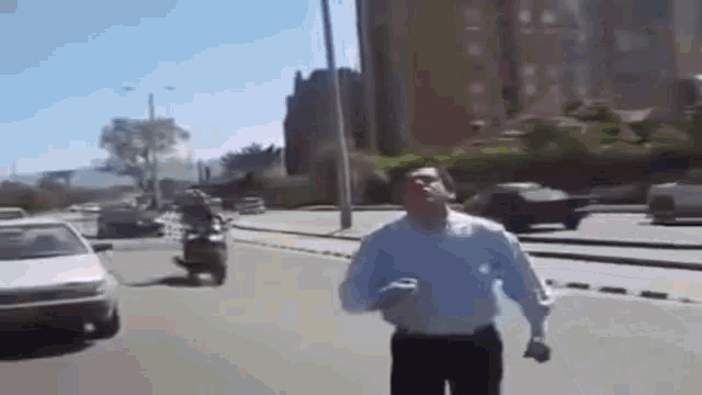 a man in a white shirt and black pants is walking down a street