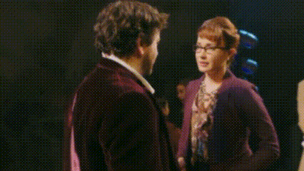 a man and a woman are looking at each other with a black background