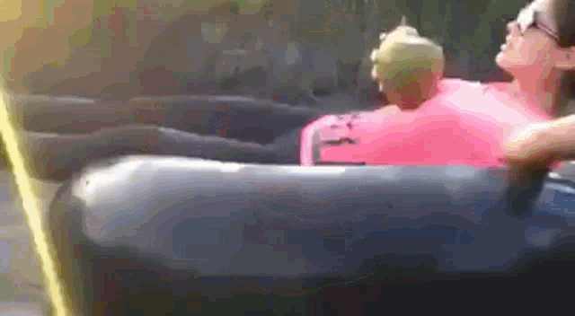 a woman in a pink shirt is sitting in a hot tub holding a coconut .