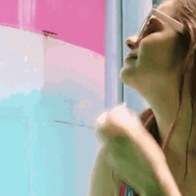 a woman wearing sunglasses is standing in a pool looking up at the sky .