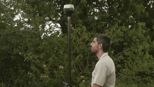 a man standing in front of a pole with a device on it