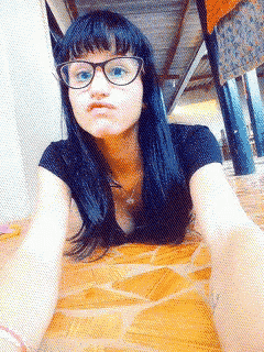 a woman wearing glasses and a black shirt is laying on a wooden floor