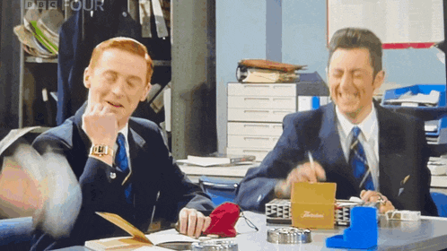 two men are sitting at a desk with a box that says floriana on it
