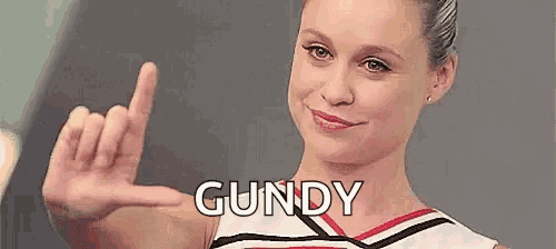 a cheerleader is giving the middle finger and the name gundy is on her chest .
