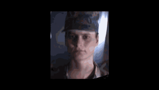 a woman in a military uniform is looking at the camera with a shadow on her face .