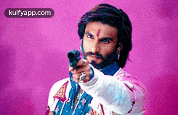 a man with a beard is pointing a gun at something .