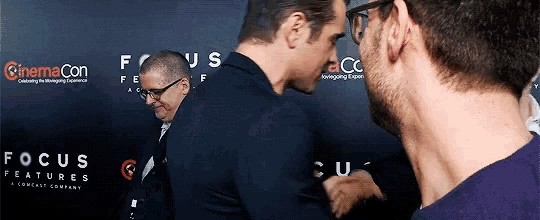 two men are standing in front of a wall that says focus on it