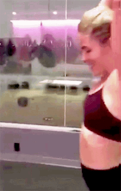 a woman in a black bra is standing in front of a mirror in a gym