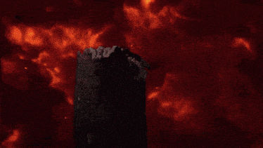 a black object is surrounded by red flames in a dark room