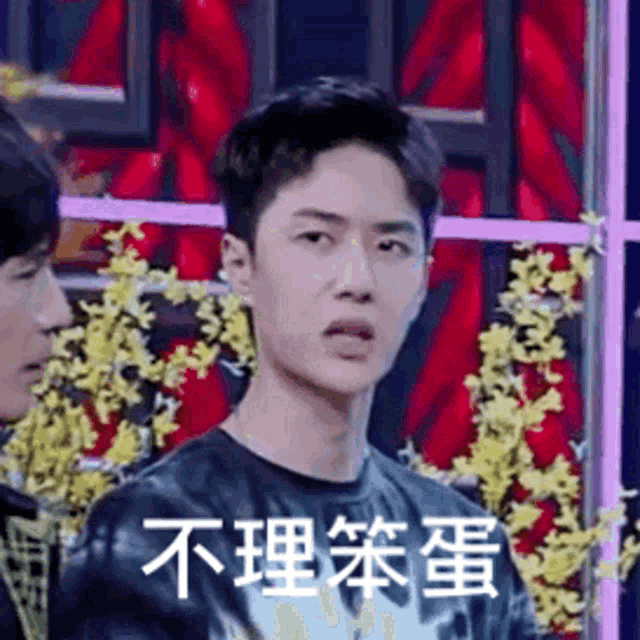 a man in a black t-shirt is making a funny face while standing next to another man .