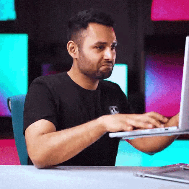 a man in a black shirt is using a laptop