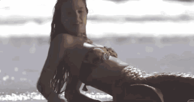 a woman in a bikini is laying on the beach looking at the ocean .