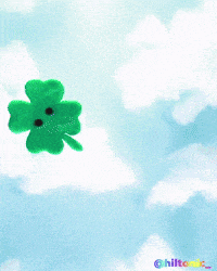 a person is holding a green four leaf clover with a sad face on it