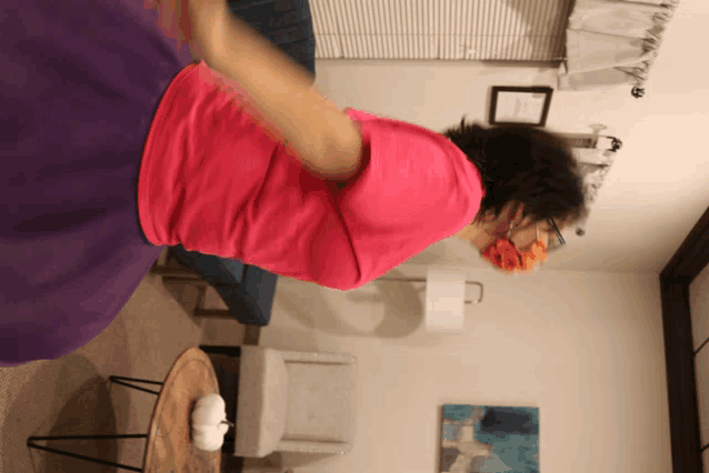 a woman in a pink shirt is sitting on a couch in a living room