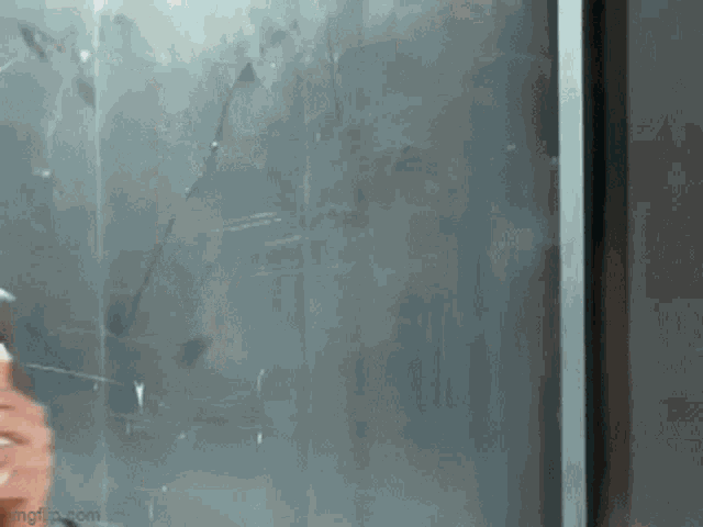 a person is standing in front of a window with a gray background .