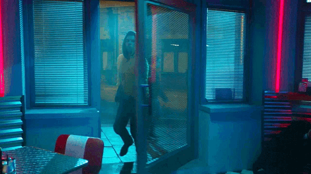 a man in a hooded sweatshirt is walking through a doorway