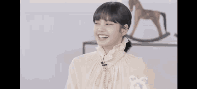 a woman in a white dress is smiling in front of a rocking horse statue .