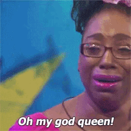 a woman wearing glasses and a pink shirt is crying and says oh my god queen