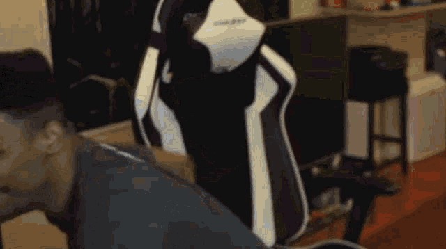 a man is sitting in a black and white gaming chair with the word dxracer on the back