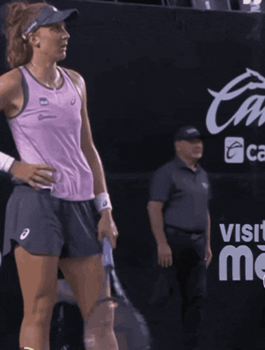a woman holding a tennis racket in front of a sign that says r
