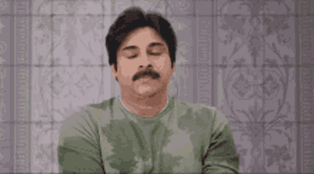 a man with a mustache is sitting in front of a tiled wall .