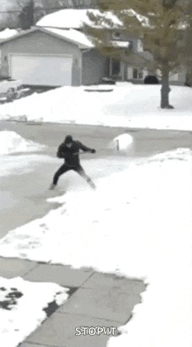 a man is throwing a snowball in the air while standing on a sidewalk .