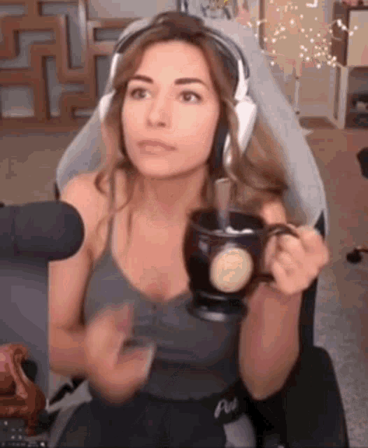 a woman wearing headphones is sitting in a chair holding a mug of coffee .