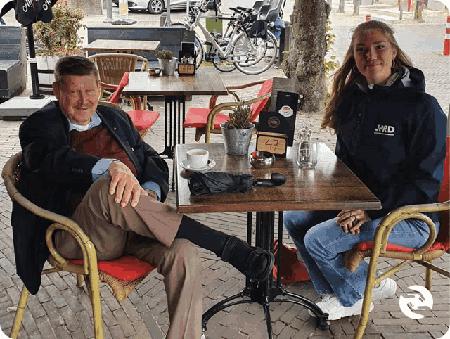 a man and woman sit at a table with a sign that says 47 on it