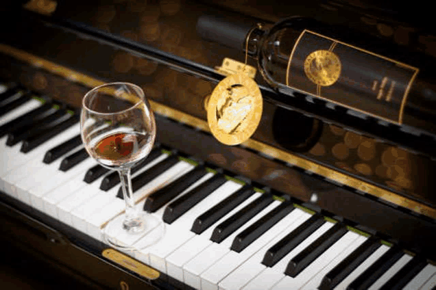 a piano with a bottle of wine and a glass of wine on it