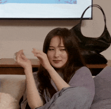 a woman laying on a couch with a purse in front of her