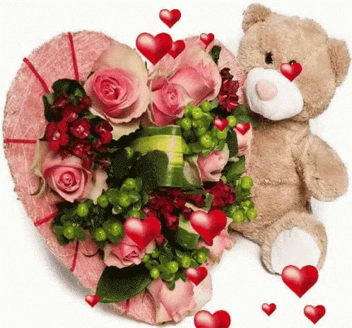 a teddy bear is sitting next to a heart shaped bouquet of roses