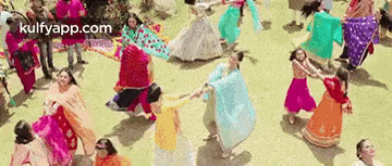 a group of people are dancing in a circle on a field .
