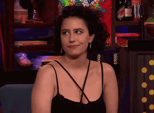 a woman sitting in front of a shelf that has a bottle of smirnoff on it