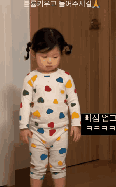 a little girl standing in front of a door wearing a colorful pajama set
