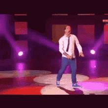 a man in a white shirt and tie is dancing on stage