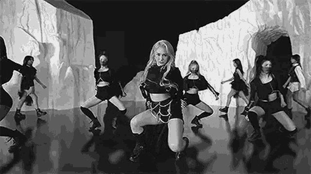a black and white photo of a group of women dancing on a stage .